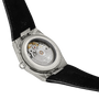 The image displays the back of a Tissot PRX 38 watch with a transparent case, showcasing its intricate automatic movement. It features a black leather strap and an engraved stainless steel case.