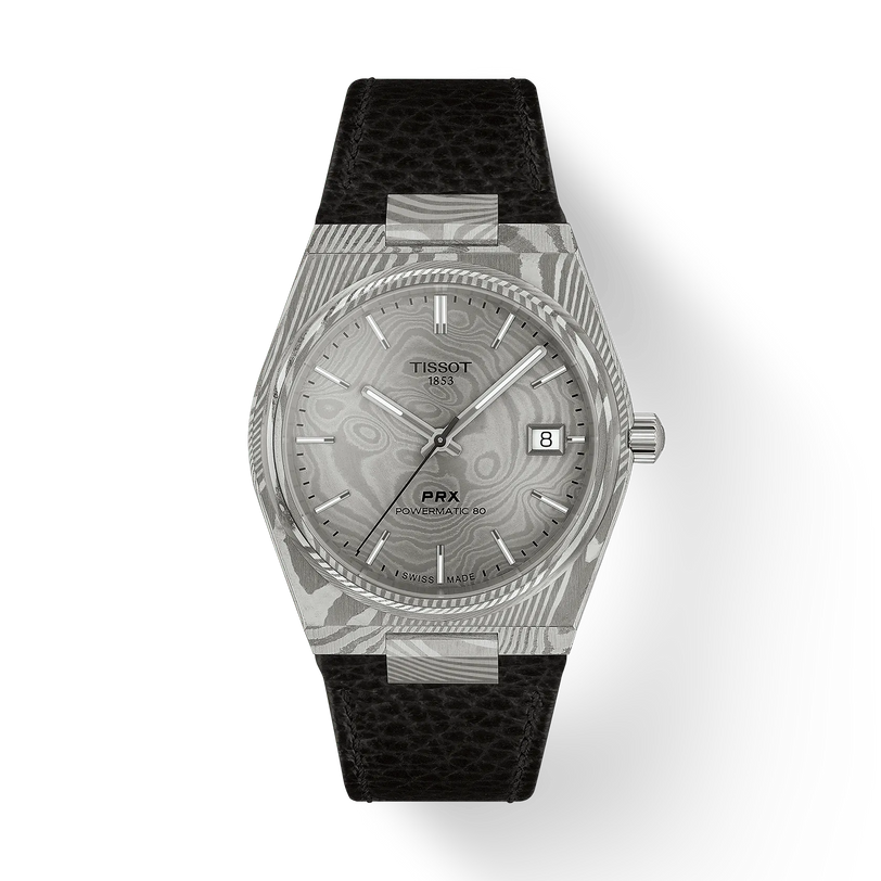 The Tissot PRX 38 features a silver case, patterned dial, date window at 3 o’clock, silver hour markers, and a black textured leather strap—an elegant choice for any Tissot enthusiast.
