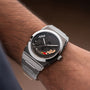 Silver watch with a unique face on a wrist against a brown background