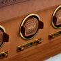Brown leather watch winder with three circular openings, gold-tone metal accents, and WOLF branding visible on leather insert