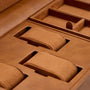 Tan leather watch winder box with three padded compartments and storage sections for jewelry or accessories.