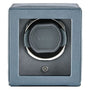 Gray leather watch winder with single circular cushioned watch holder and power button.