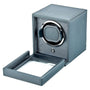 Gray leather watch winder with single rotating watch holder and open cover, showing interior mechanism.