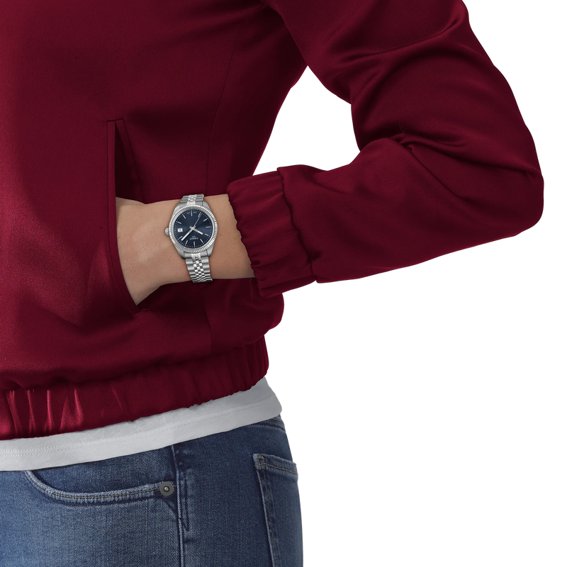 Person wearing a red jacket and blue jeans with a silver watch on a white background