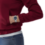Person wearing a red jacket and blue jeans with a silver watch on a white background