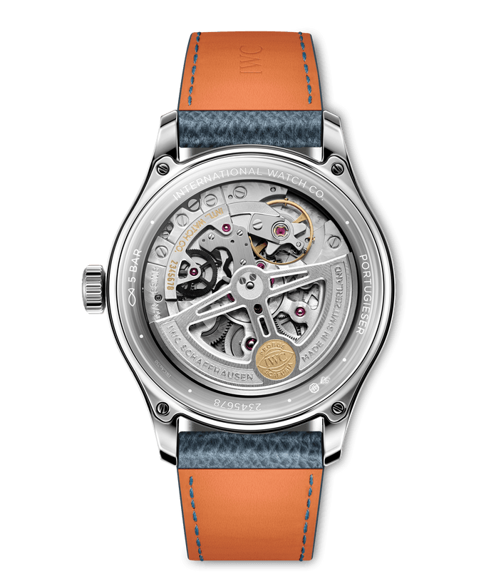 A close-up of the back of the 40mm IWC Schaffhausen Portugieser Automatic 40 reveals its intricate movement, silver case with transparent back, blue and orange leather strap, and engravings of International Watch Co and Portugieser.