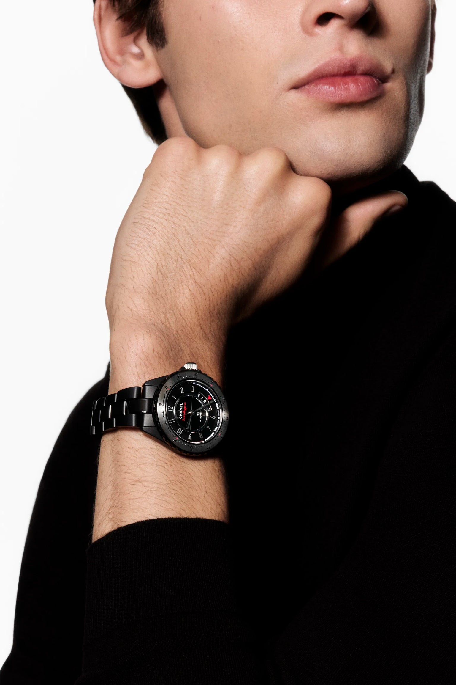 Black ceramic sports watch with dark dial worn on man's wrist against black sleeve.