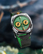 Wristwatch with unique green face and black strap on a blurred background