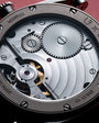 Close-up of watch movement showing tourbillon mechanism with exposed gears, balance wheel, and gold-colored rotor on silvered