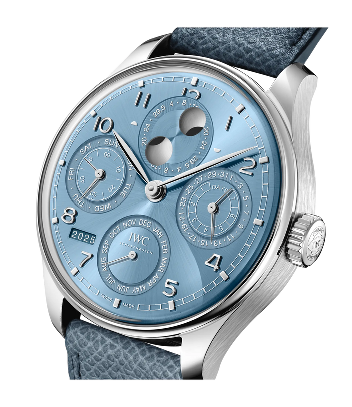 The IWC Schaffhausen Portugieser Perpetual Calendar 44 features a light blue face, silver case, blue textured strap, multiple subdials, moon phase display, and a 2025 year window.