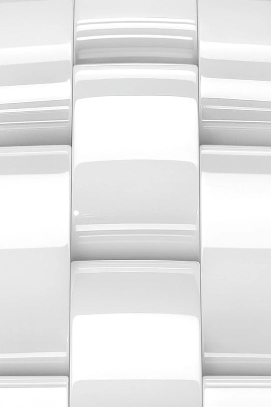 Close-up view of glossy, white rectangular ceramic tiles arranged in a staggered pattern, showcasing high precision and smooth surfaces inspired by the refined craftsmanship of Chanel’s J12 collection.