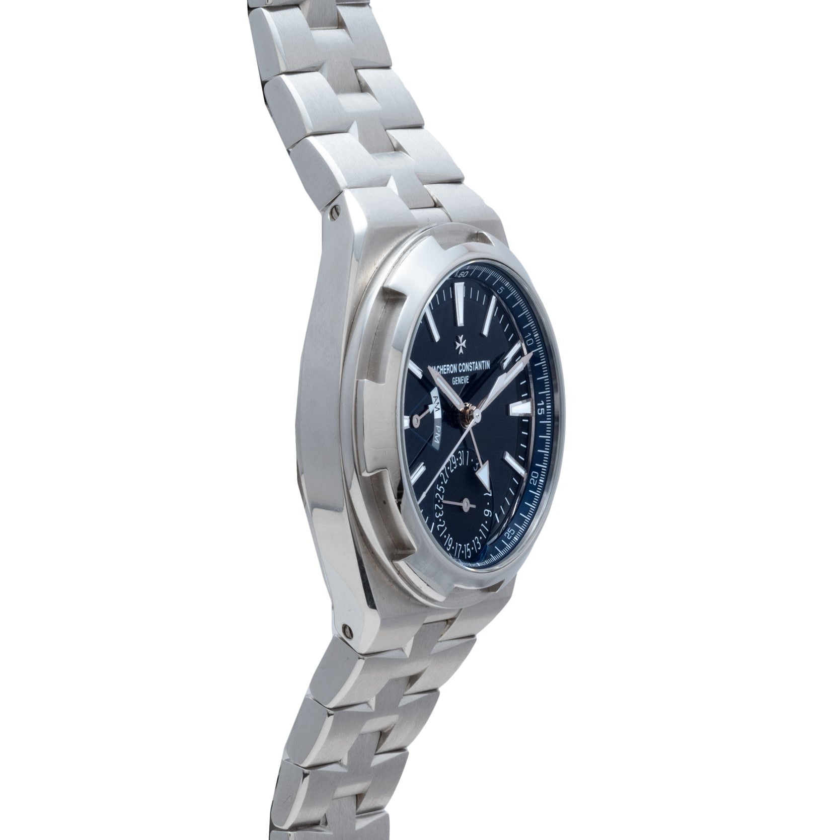 The Vacheron Constantin Overseas Dual-Time wristwatch features a blue dial and metal bracelet, displayed at an angle on a white background.