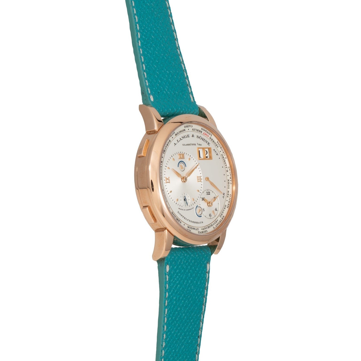 The Lange & Sohne Lange 1 Timezone wristwatch features a gold case, white dial, and blue leather strap, displayed at an angle against a white background.