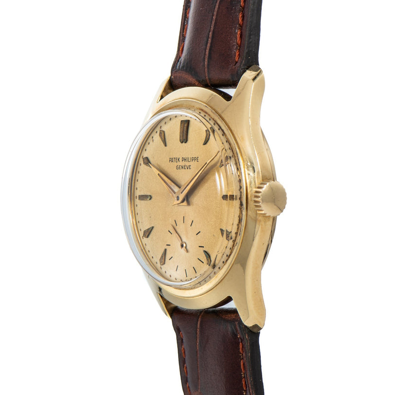 Patek Philippe Calatrava gold wristwatch with a worn dial and brown leather strap, viewed from an angle.