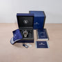 Grand Seiko watch in an open box with accessories on a beige surface