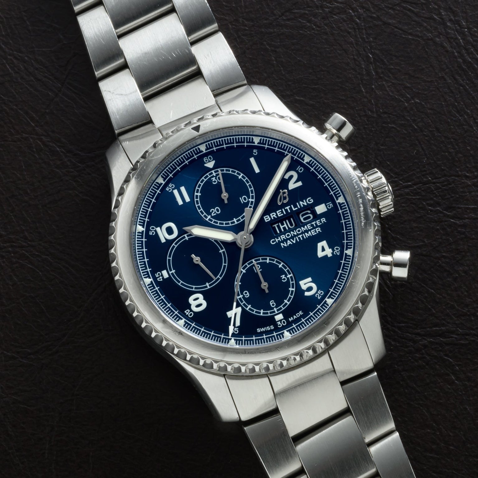 Breitling Navitimer 8 Chronograph watch with a blue dial and metal bracelet, displayed on a dark surface.