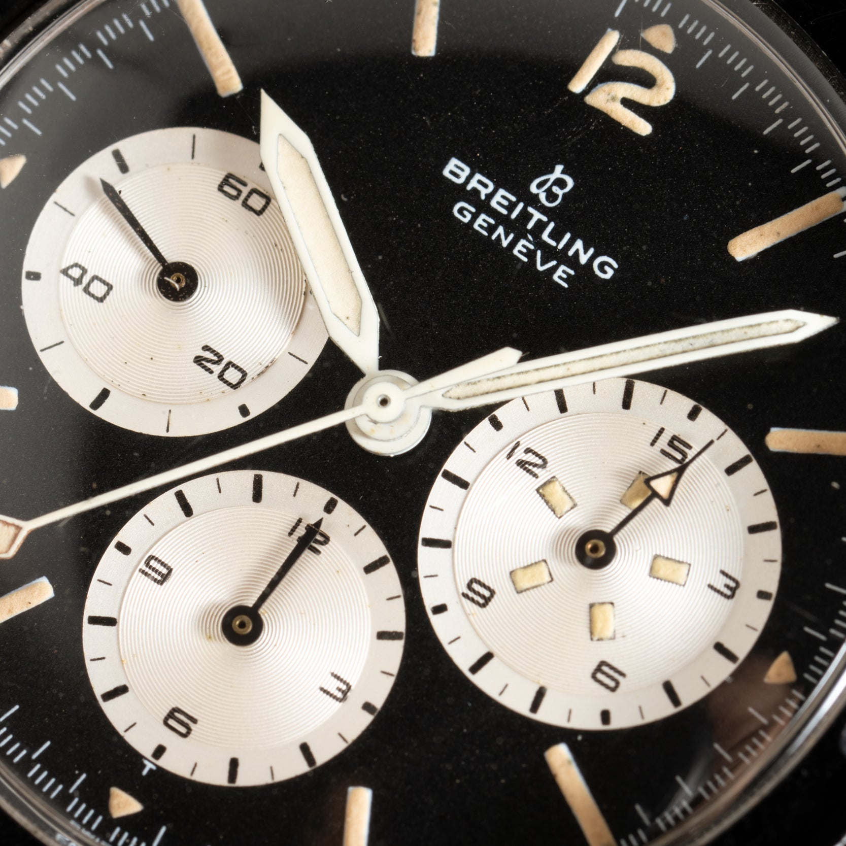 Close-up of a black Breitling Co-Pilot Chronograph watch face with three subdials and white hands.