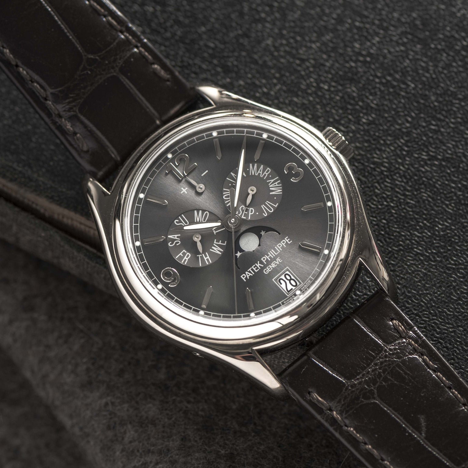 A Patek Philippe Annual Calendar Moonphase wristwatch featuring a black leather strap and detailed dial displaying the date and day.