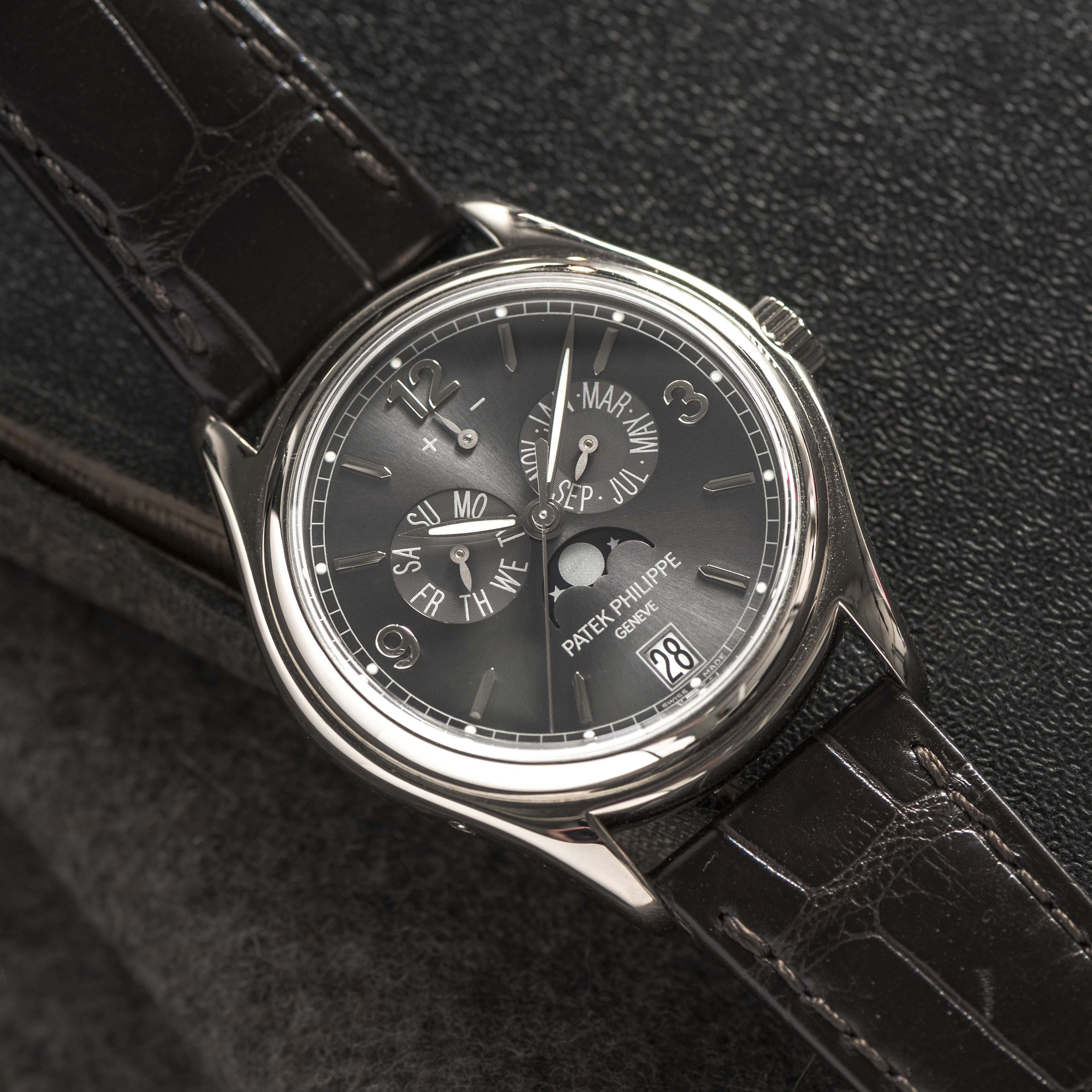 A Patek Philippe Annual Calendar Moonphase wristwatch featuring a black leather strap and detailed dial displaying the date and day.