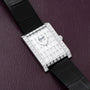 Piaget Limelight Baguette Diamond Dress Watch with black leather strap displayed on a textured burgundy surface.