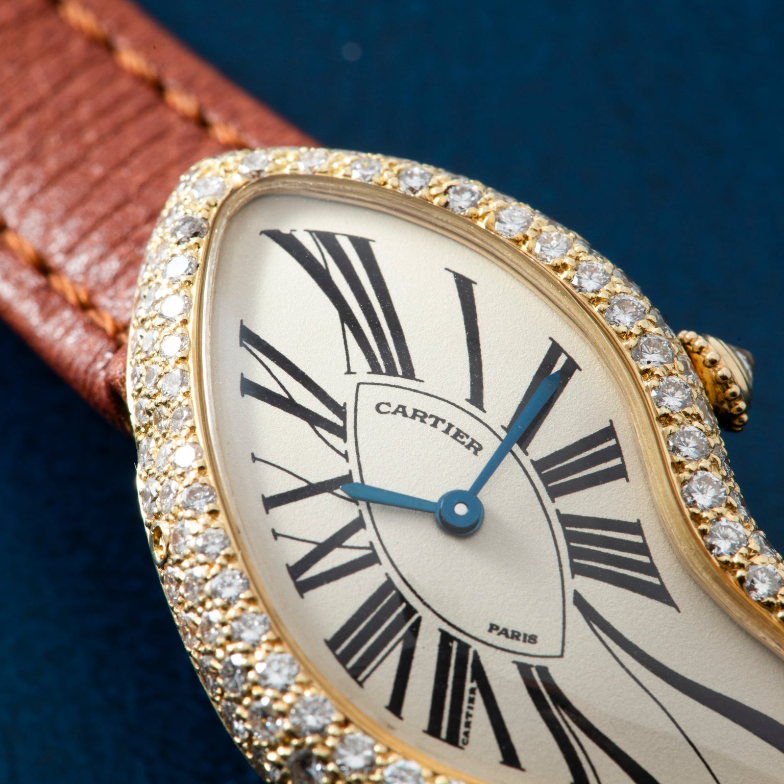 Close-up of the Cartier Crash Diamonds watch, featuring a distorted face, diamond bezel, and brown leather strap.