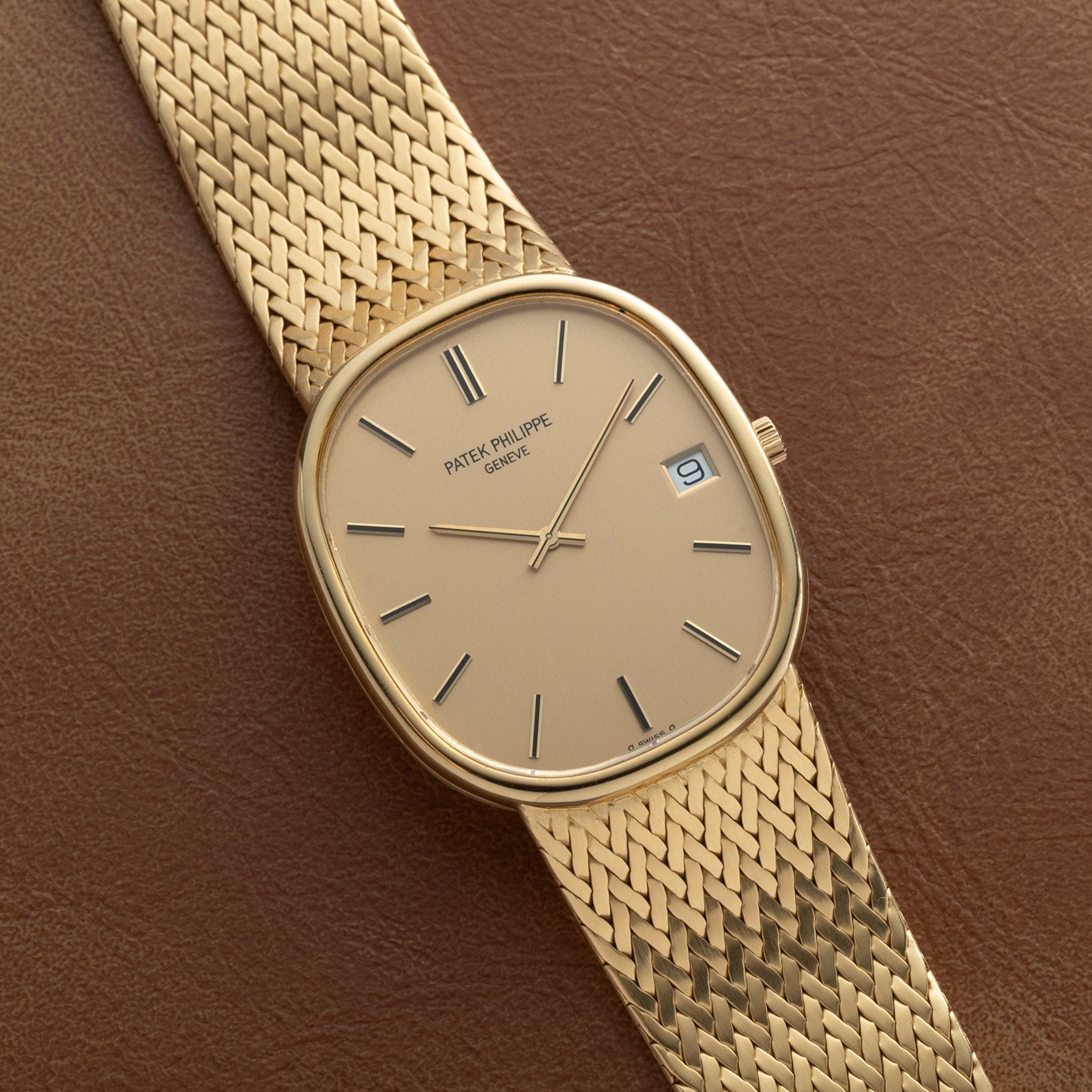 Patek Philippe Ellipse Jumbo with mesh band and date display, shown on a brown leather surface.