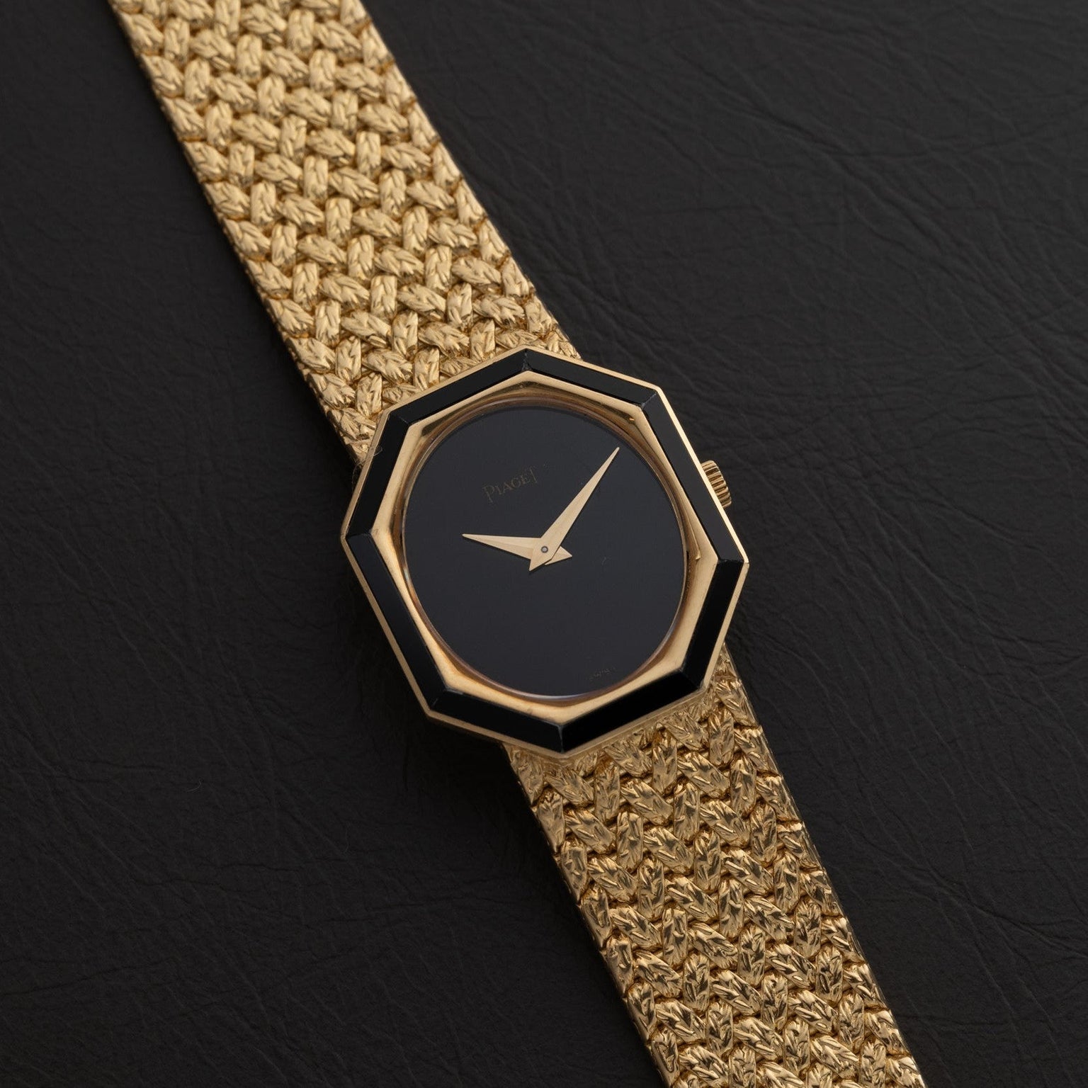 The Piaget Onyx Dial wristwatch features a black octagonal face without hour markers, set on a textured gold band and pictured against black leather.