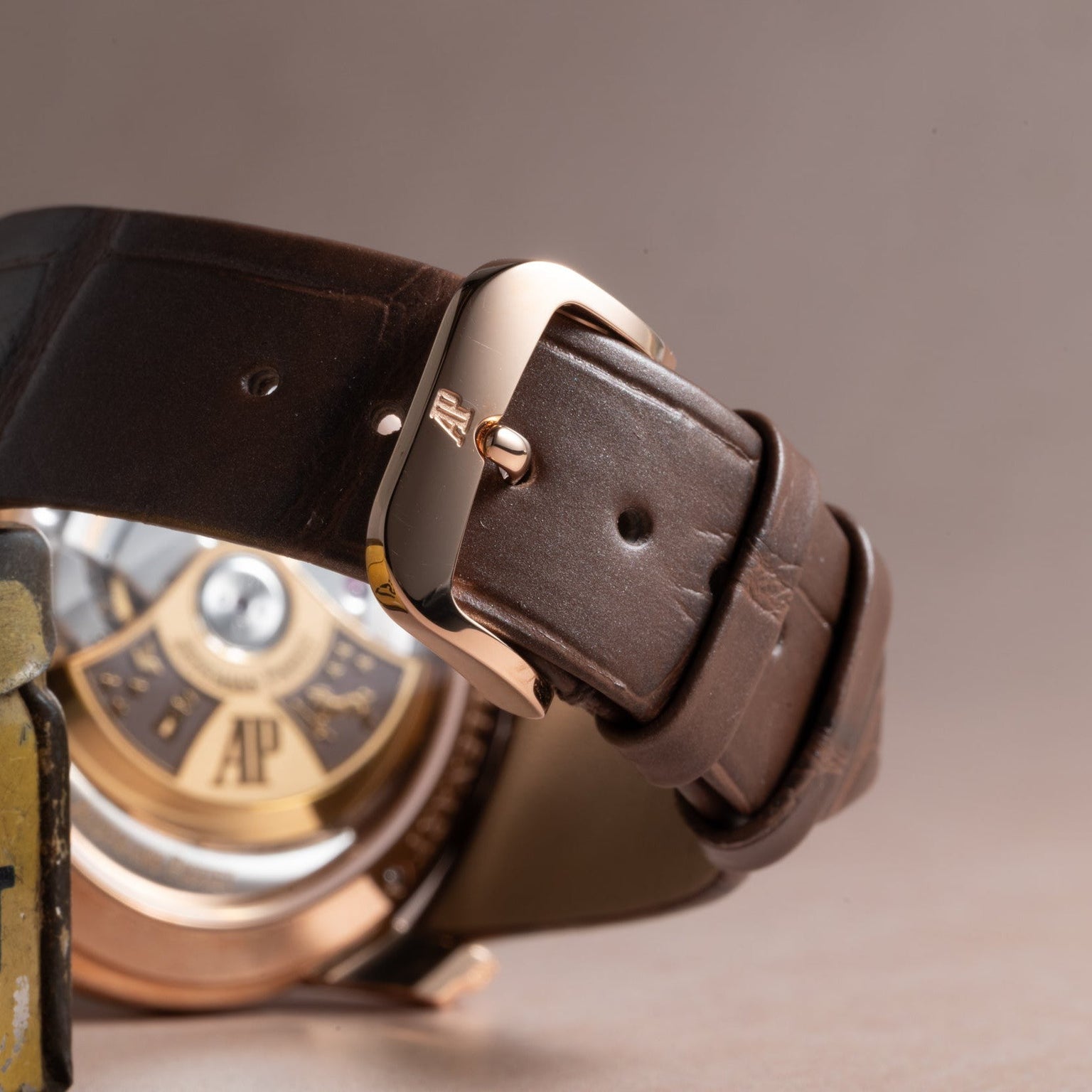 Close-up of the brown leather strap and AP-engraved buckle on an Audemars Piguet Millenary Philosophique, with the watch’s movement visible in the background.