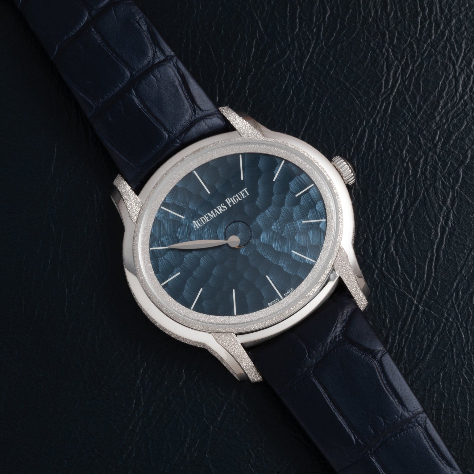 The Audemars Piguet Millenary Philosophique is a luxury watch featuring a blue textured dial and a dark blue leather strap.