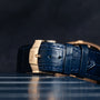 Close-up of the Piaget Black Tie Andy Warhol blue leather watch strap with a gold clasp, set against a dark background.