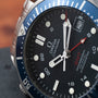 Close-up of an OMEGA Seamaster 300 Professional GMT watch featuring its face, hands, date window, and blue bezel.