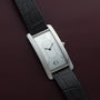 Cartier Tank Cintrée Limited Edition wristwatch with a black leather strap displayed on a dark maroon leather surface.