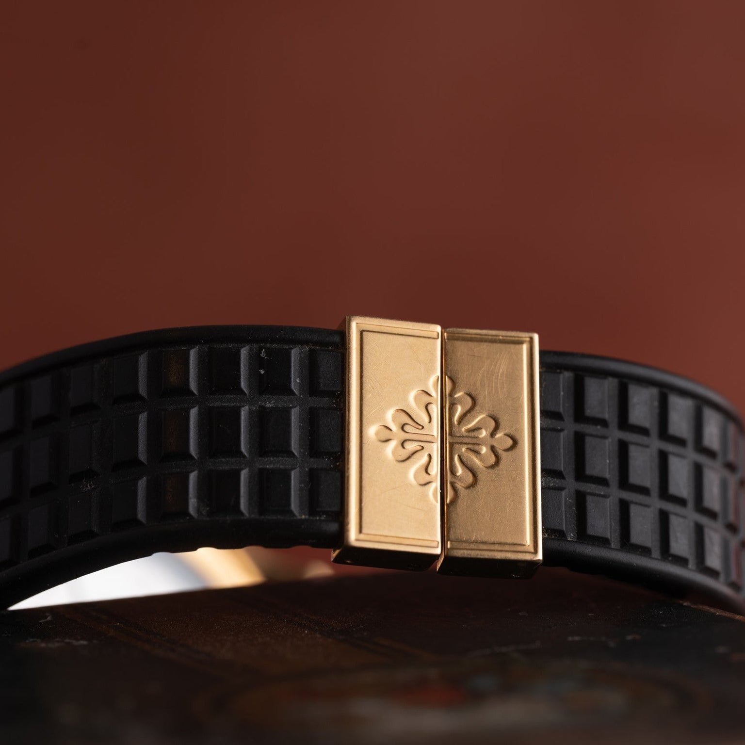 Close-up of the Patek Philippe Aquanauts black textured strap, showcasing a gold clasp with ornate engraving.