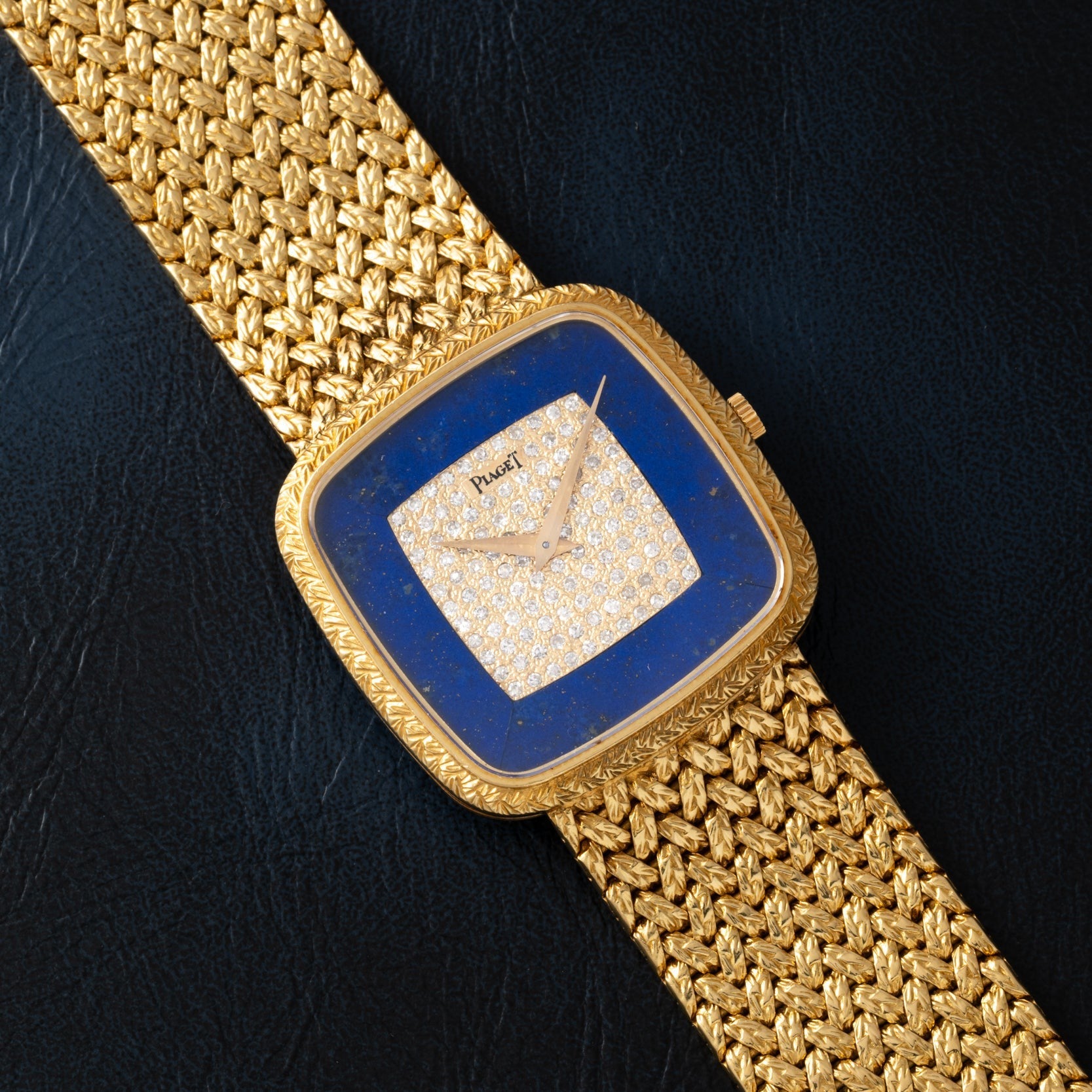 Piaget Pave Lapis Lazuli Dress Watch with a diamond-studded blue square face and textured gold band, displayed on a dark surface.