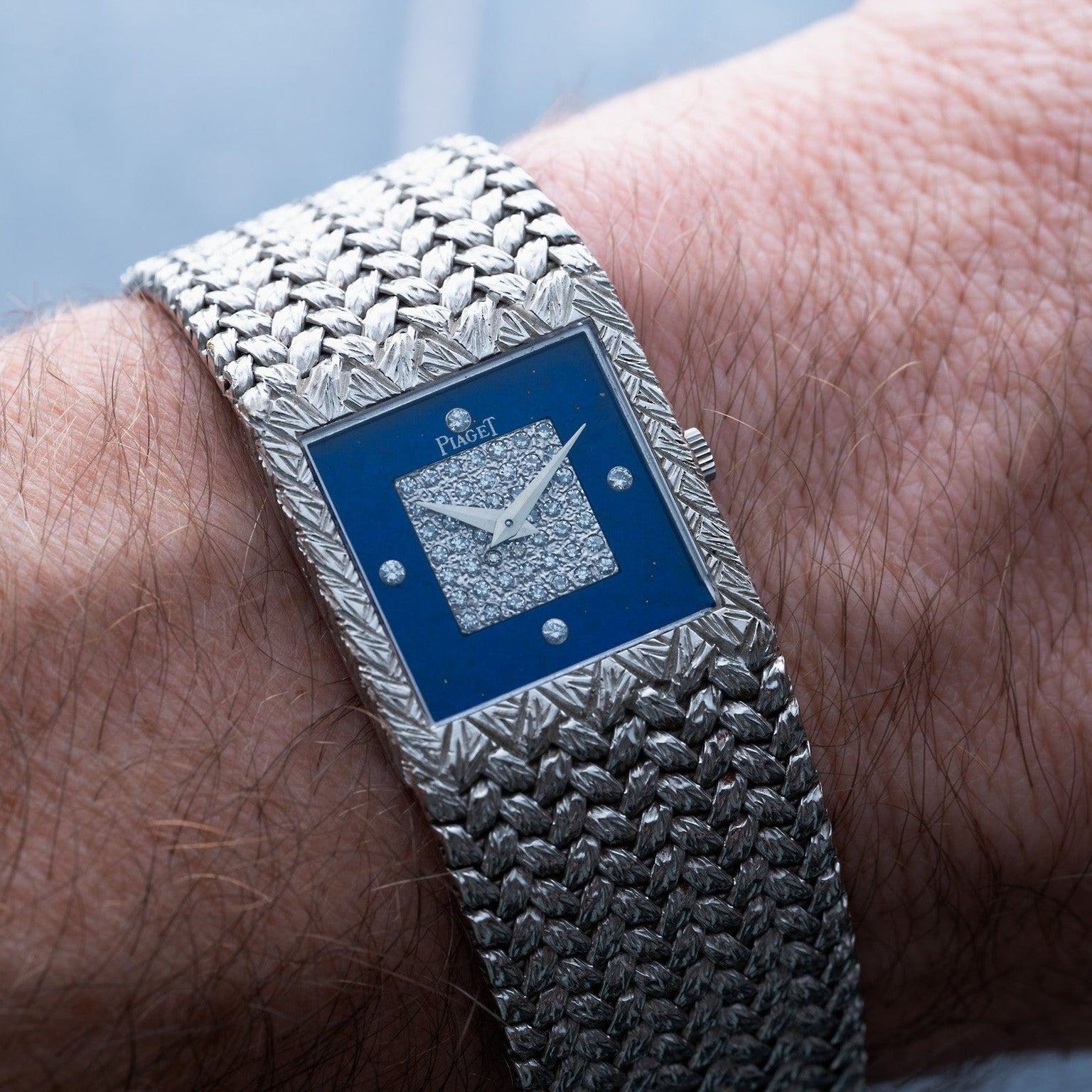 A Piaget Tradition Lapis Lazuli Diamond Dress Watch with a blue, diamond-encrusted face is worn on a persons wrist.