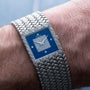 A Piaget Tradition Lapis Lazuli Diamond Dress Watch with a blue, diamond-encrusted face is worn on a persons wrist.