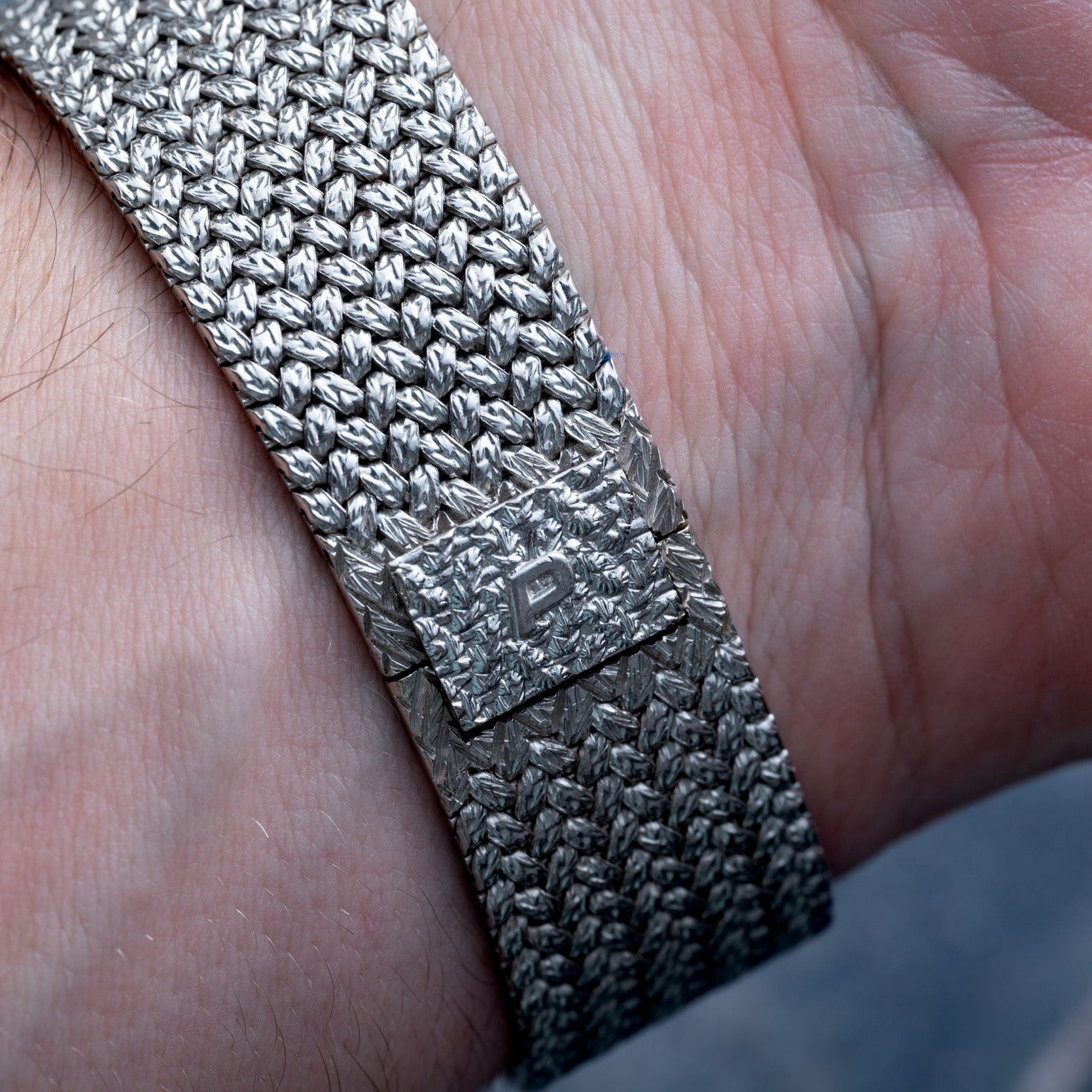 Close-up of a Piaget Tradition Lapis Lazuli Diamond Dress Watch, featuring a textured silver bracelet and a clasp marked with a P on the wearer’s wrist.