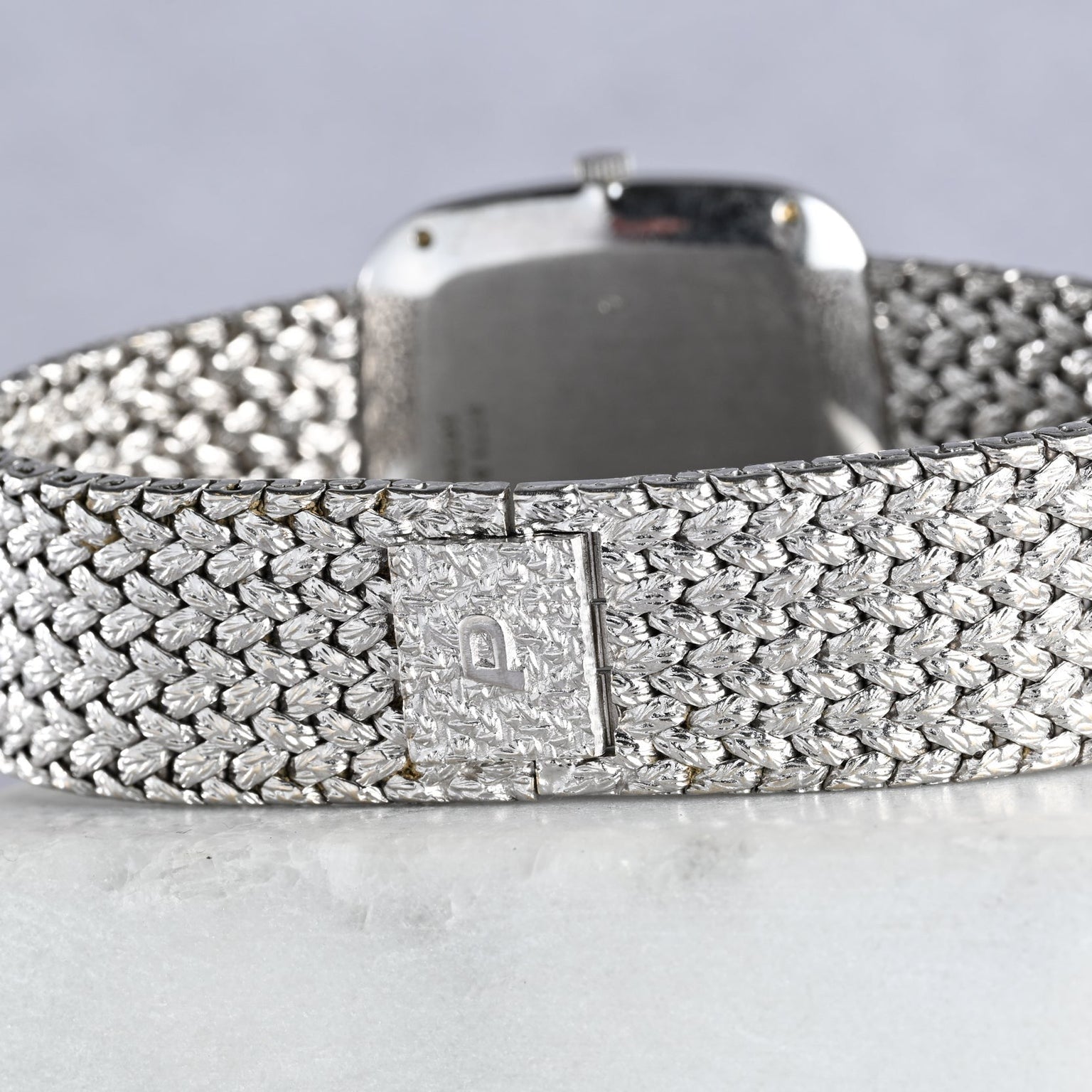 Close-up of the Piaget Hawk Eye White Gold Dress Watch, showing its textured white gold bracelet with a rectangular clasp on a light surface.