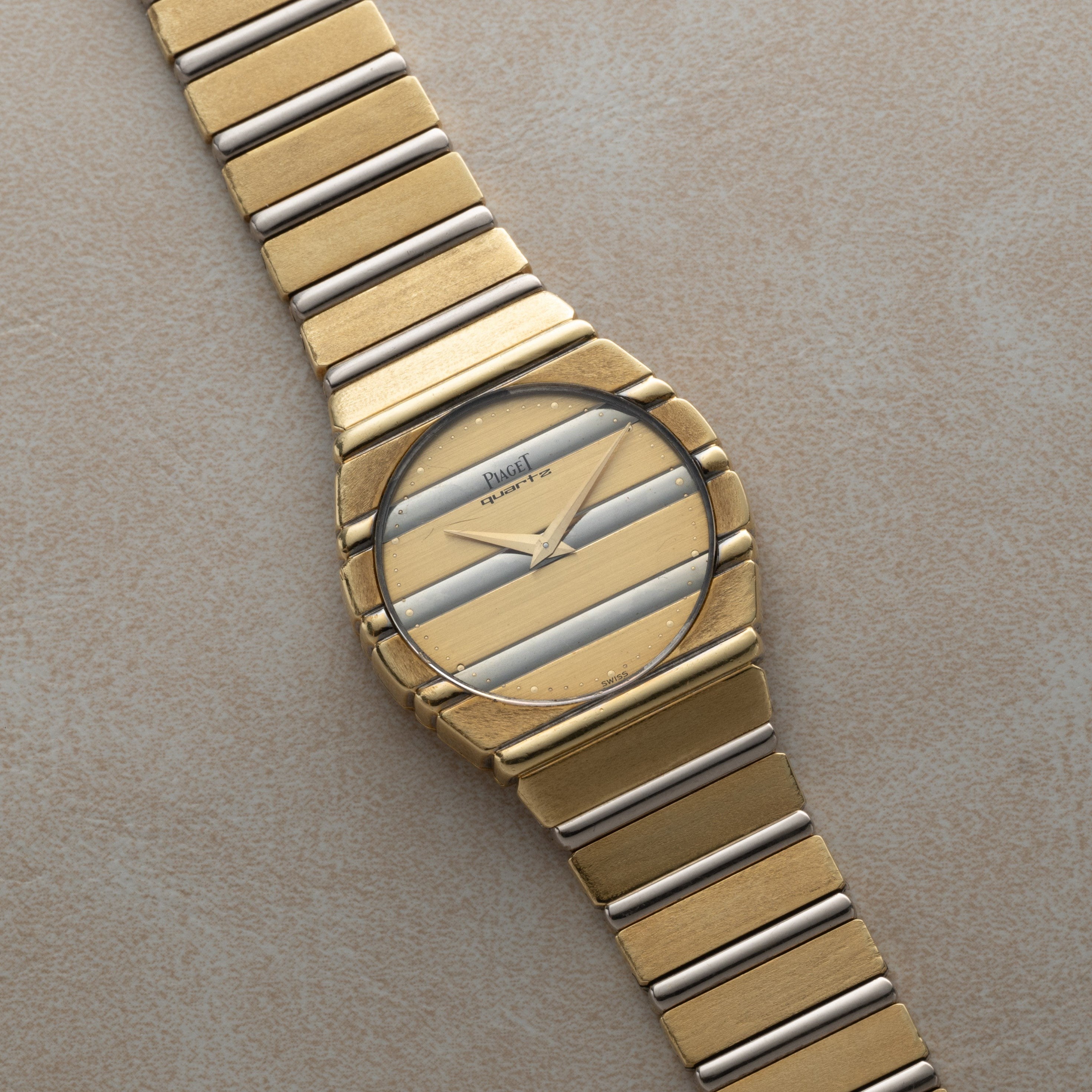 The Piaget Polo Two-Tone is a gold wristwatch featuring diagonal gold and silver stripes on its face with a matching striped metal band.