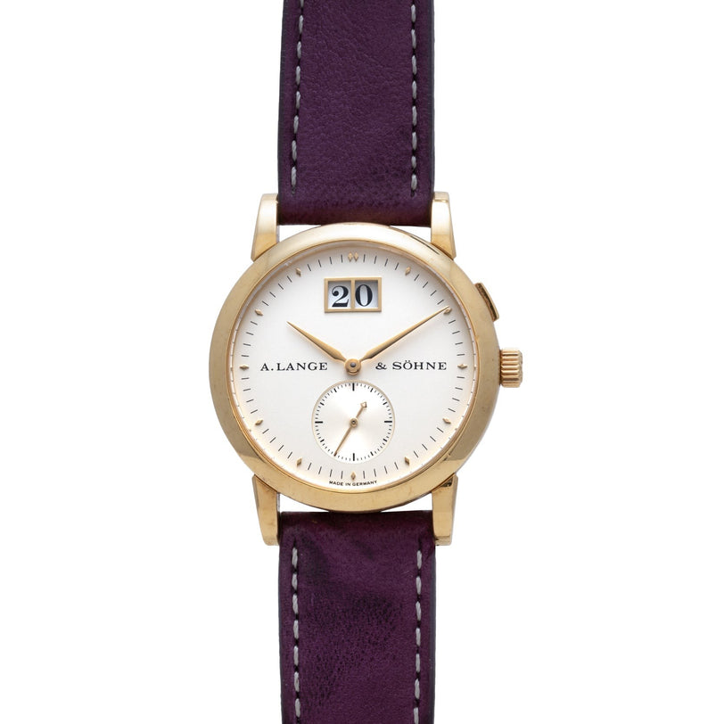 Lange & Sohne Saxonia Outsize Date gold wristwatch with white dial, purple leather strap, date window, and small seconds subdial.