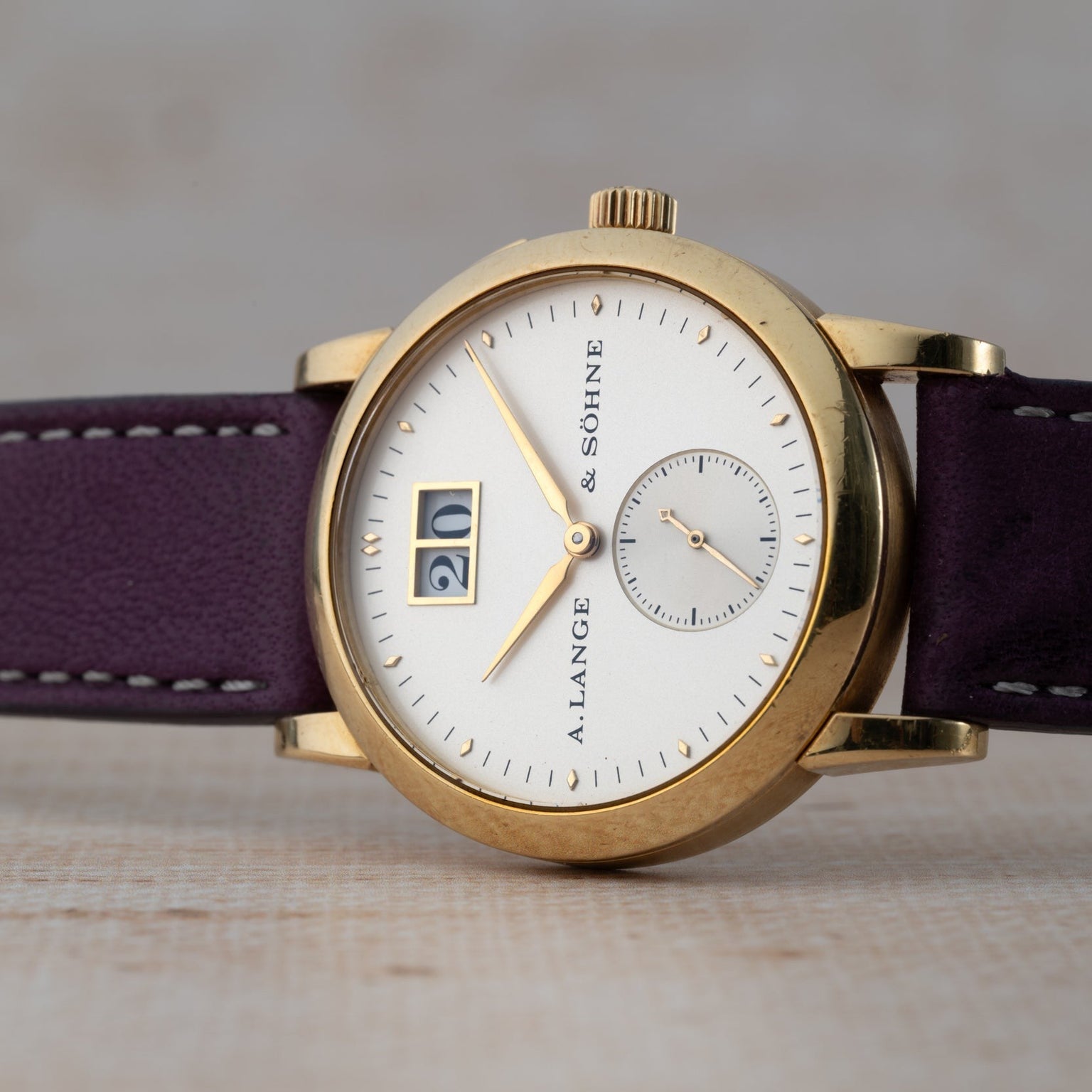 The Lange & Sohne Saxonia Outsize Date features a white dial, purple leather strap, and a prominent date display.