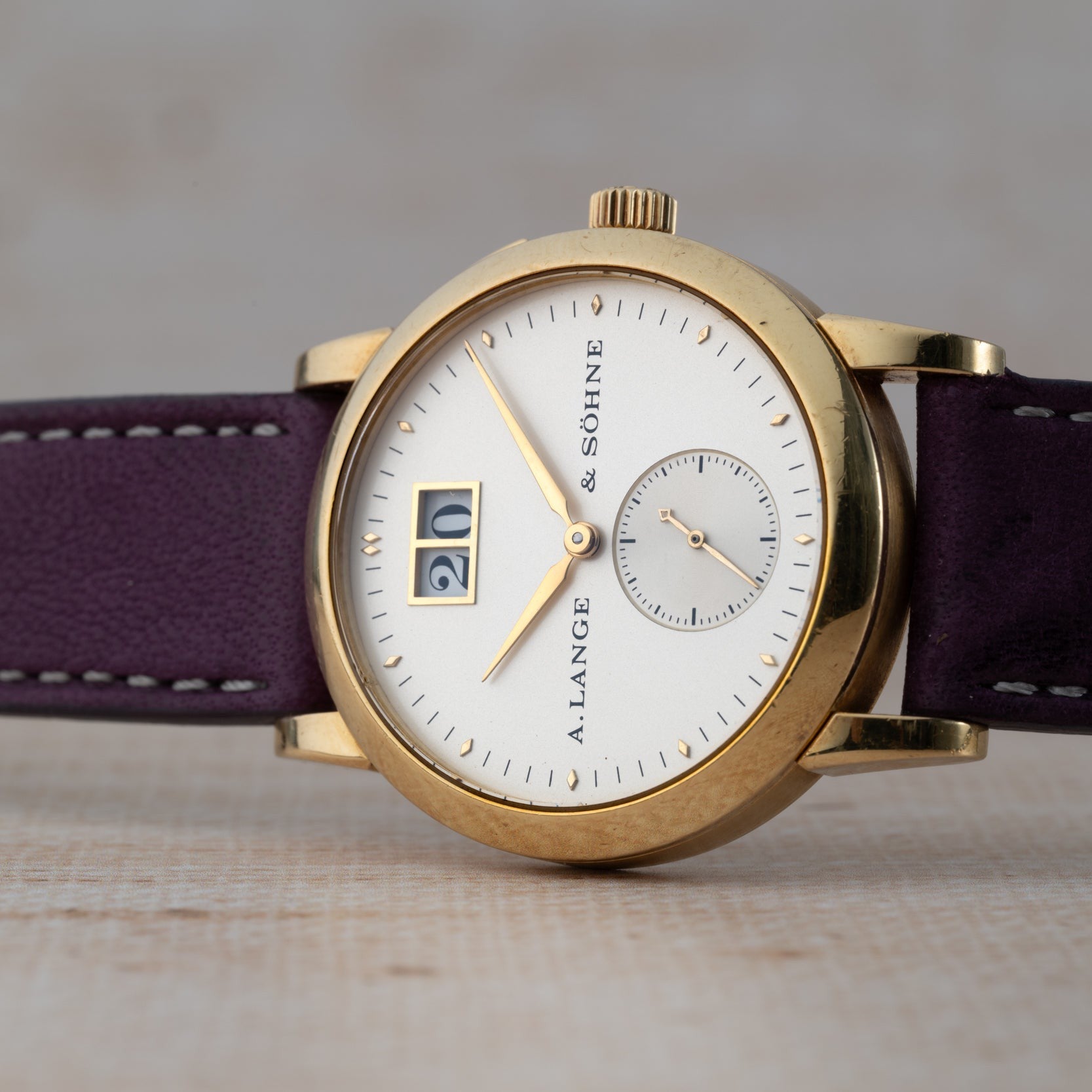 The Lange & Sohne Saxonia Outsize Date features a white dial, purple leather strap, and a prominent date display.