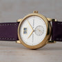 The Lange & Sohne Saxonia Outsize Date features a white dial, purple leather strap, and a prominent date display.