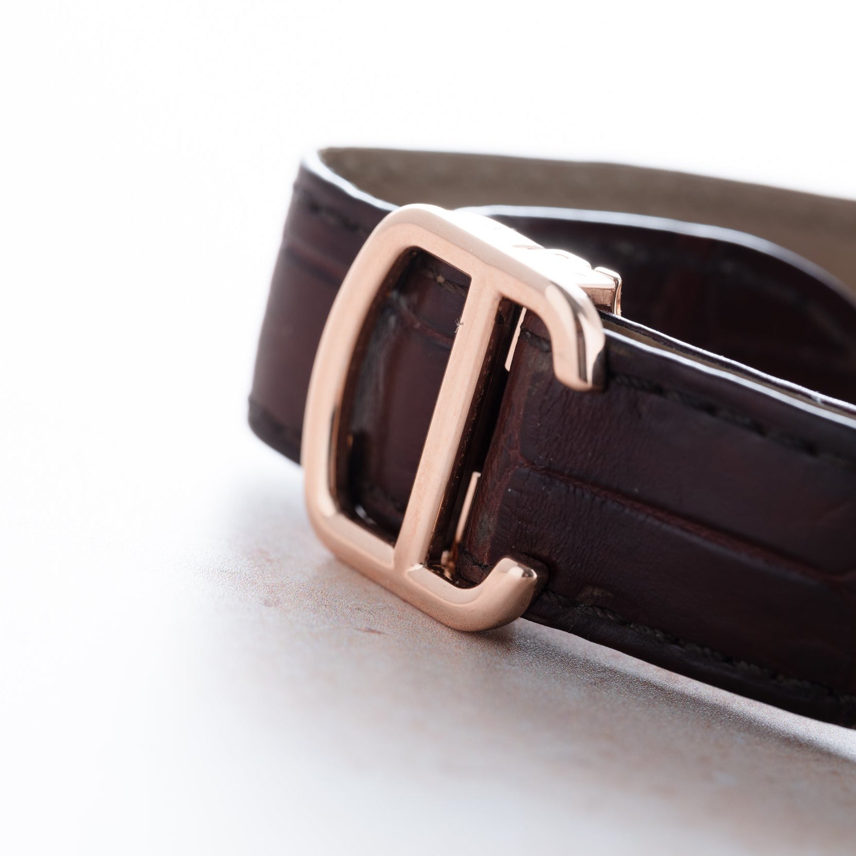 Close-up of the Cartier Tank Cintreé Skeleton watch with a brown leather strap and gold buckle on a light surface.