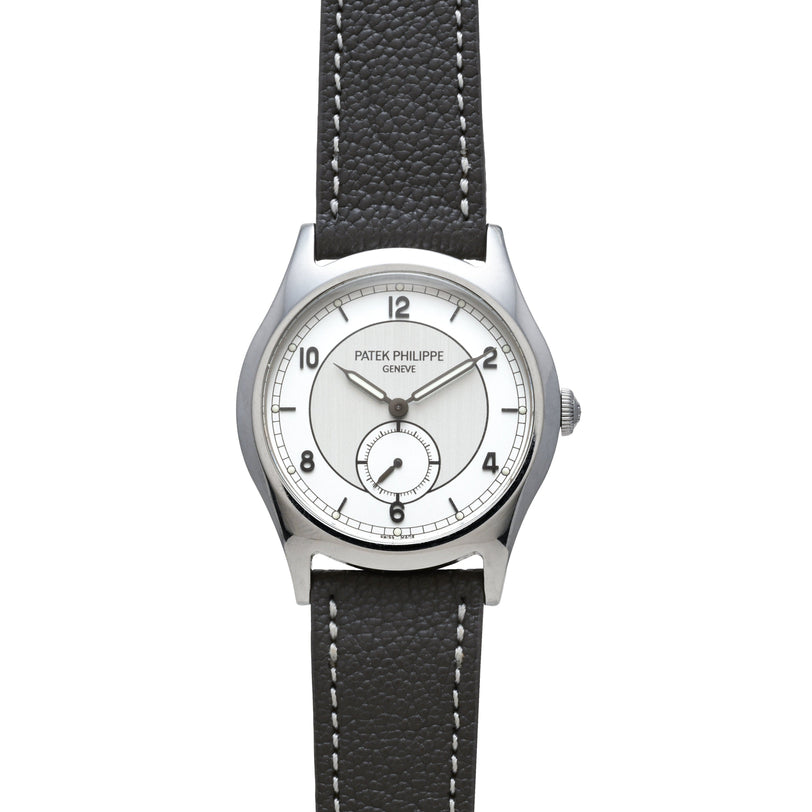 A Patek Philippe Calatrava Geneva Boutique Limited Edition wristwatch with a silver case, white dial, and black leather strap displays the time 12:10.