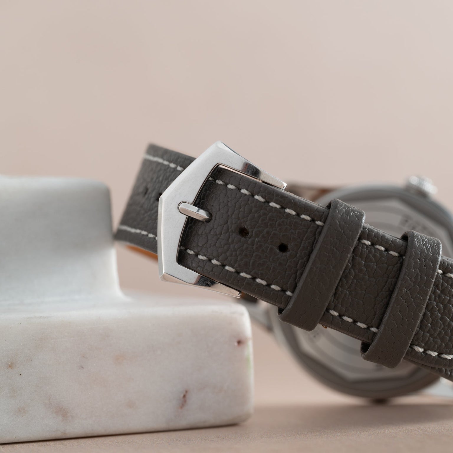 Close-up of the Patek Philippe Calatrava Geneva Boutique Limited Edition gray leather strap with a silver buckle, resting on a white marble surface.