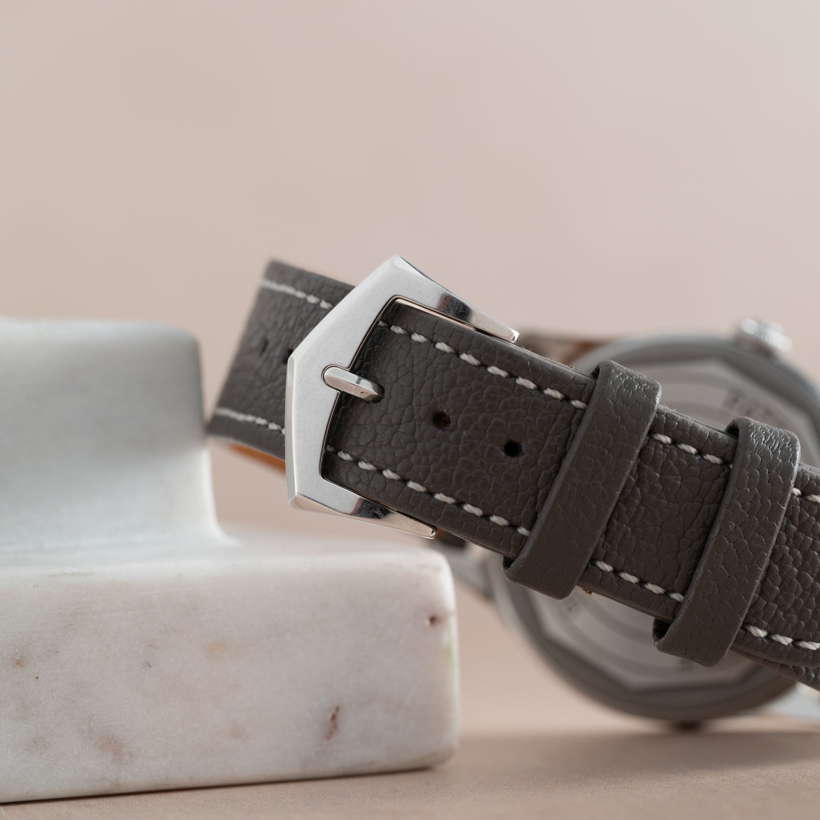 Close-up of the Patek Philippe Calatrava Geneva Boutique Limited Edition gray leather strap with a silver buckle, resting on a white marble surface.