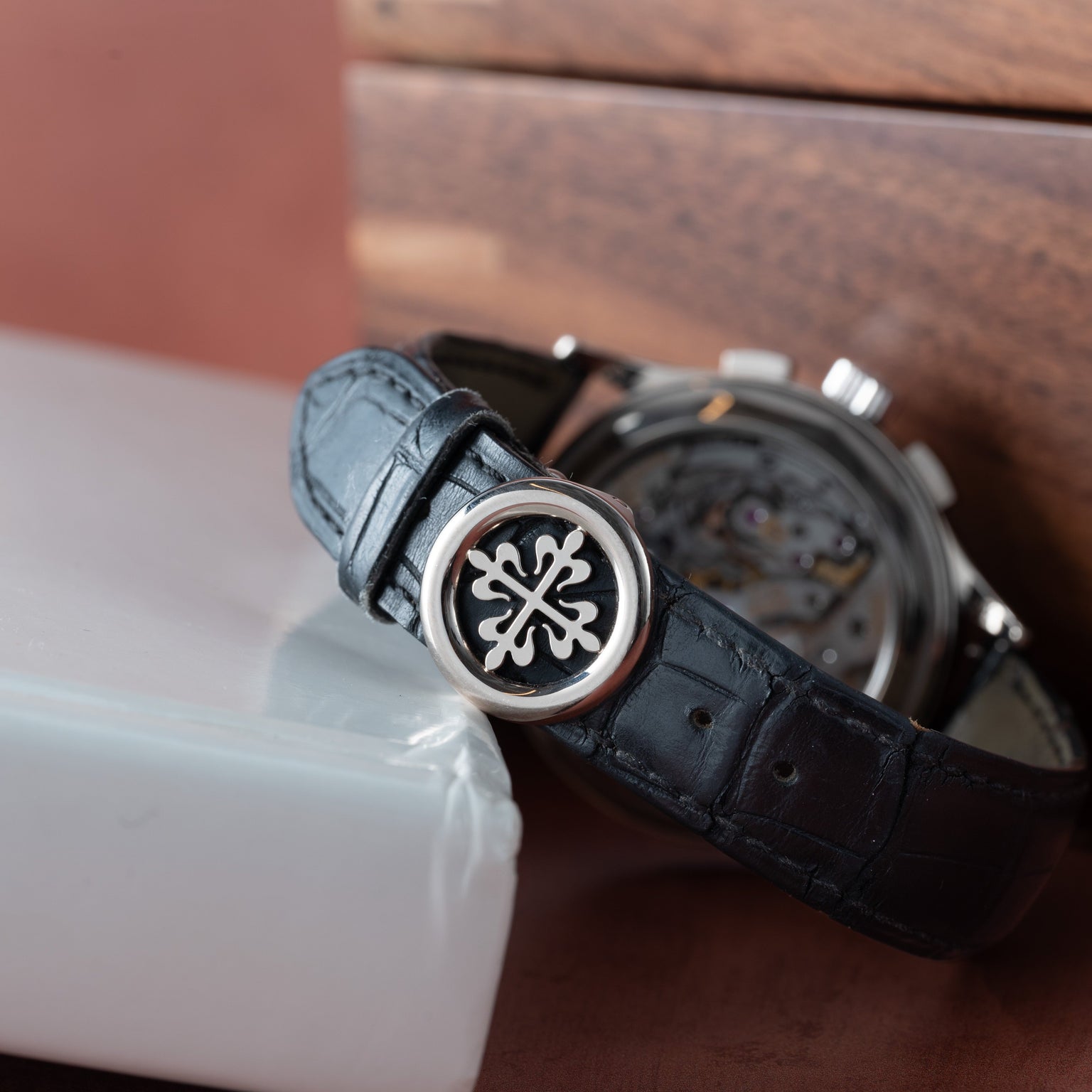 Close-up of a Patek Philippe Chronograph featuring a black leather strap and detailed silver buckle, elegantly resting on a white box.