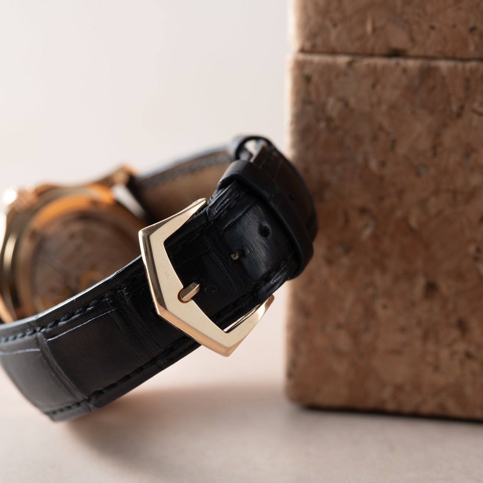 Close-up of the Patek Philippe Aquanaut’s black leather strap with a gold buckle, shown resting on a cork surface.