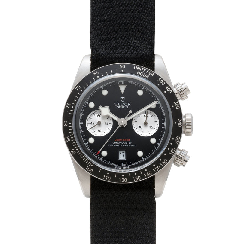 The TUDOR Black Bay Chronograph is a black wristwatch with a black strap and two white subdials on its face.